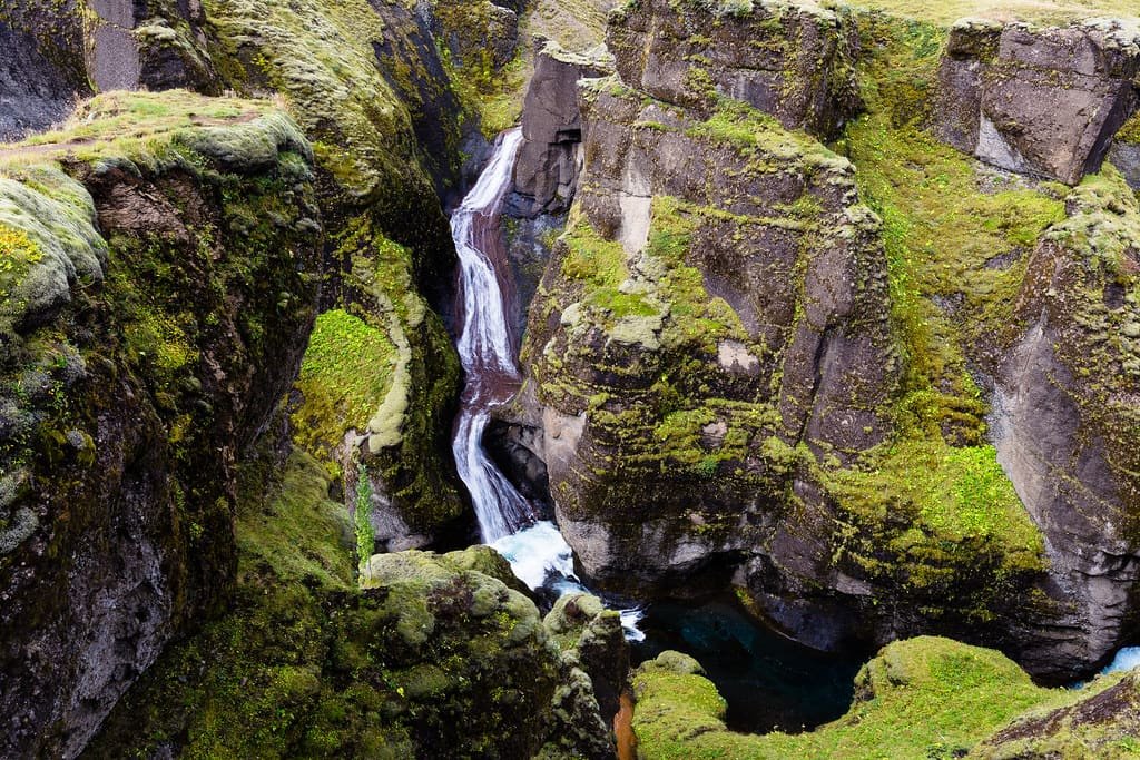 A waterfall dropping through a narrow green gorge
