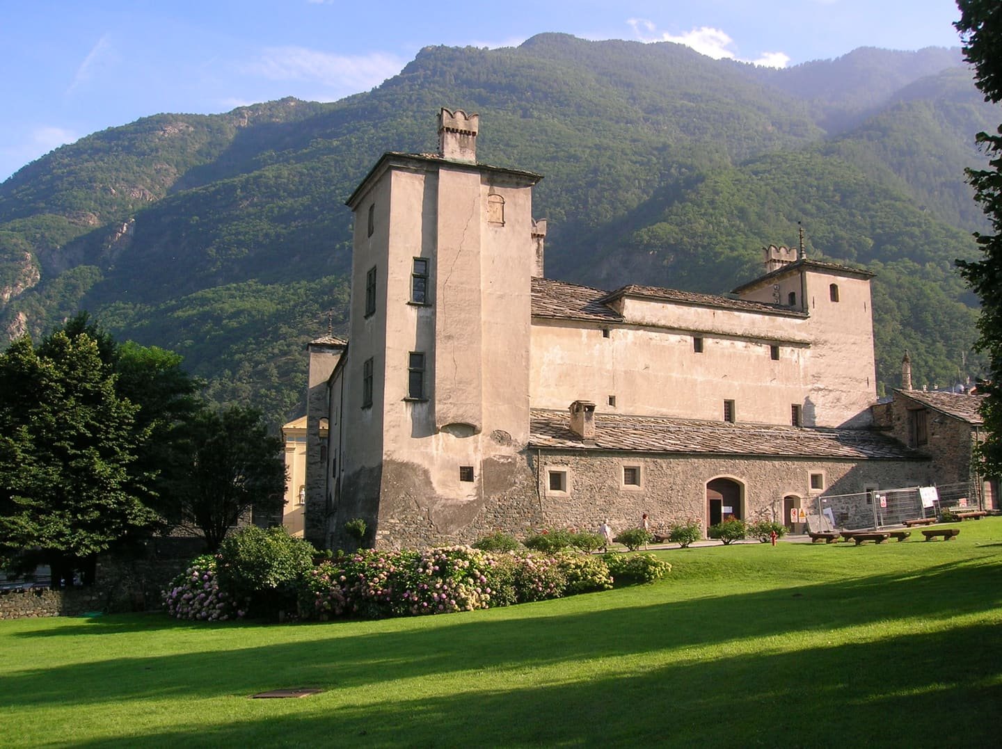 A pale stone castle with corner towers above the valley
