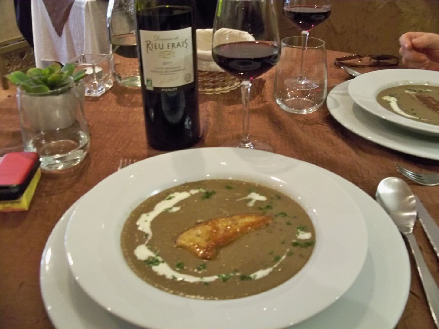 Soup and a glass of red wine on a wooden table