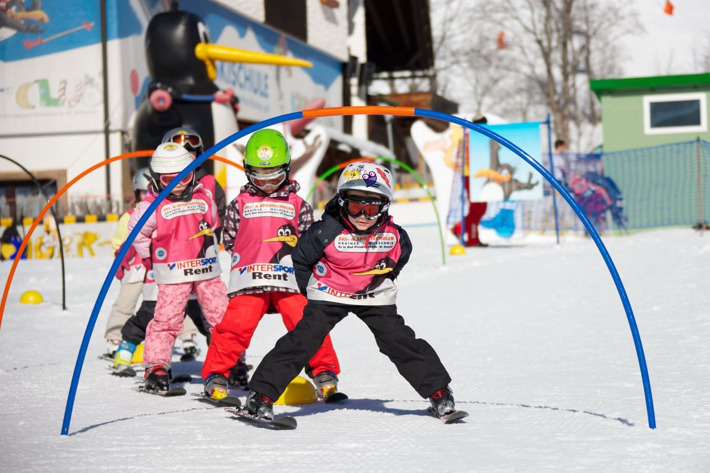 Children skiing through coloured hoops in a resort snow garden