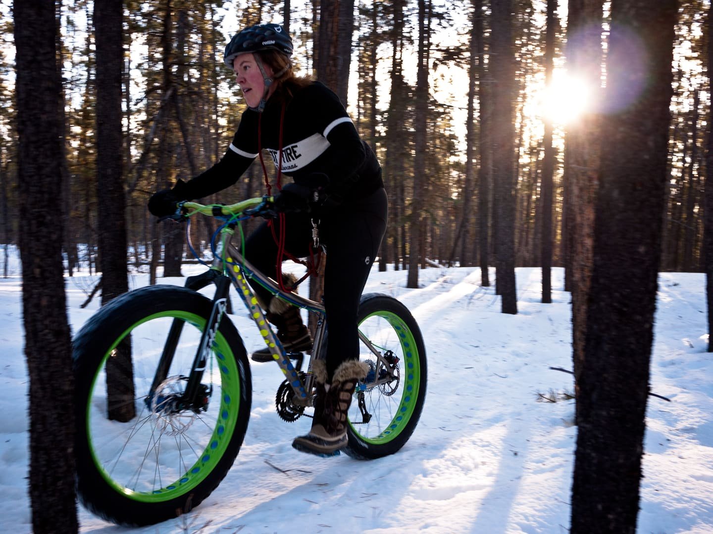Un ciclista su una fat bike lungo una pista forestale innevata