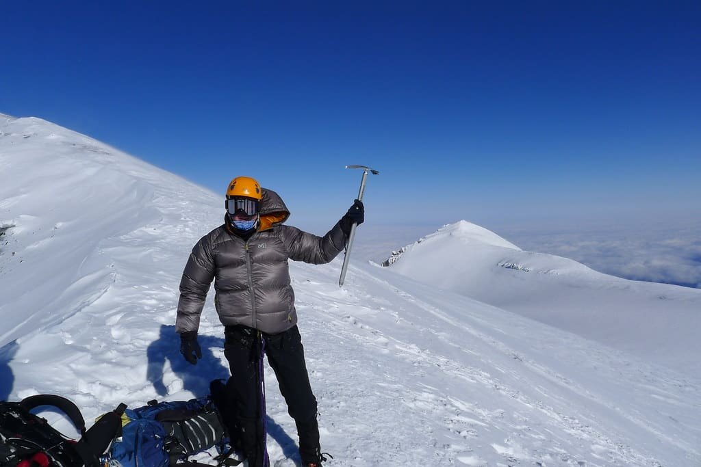 A mountaineer on a summit ridge holding an ice axe