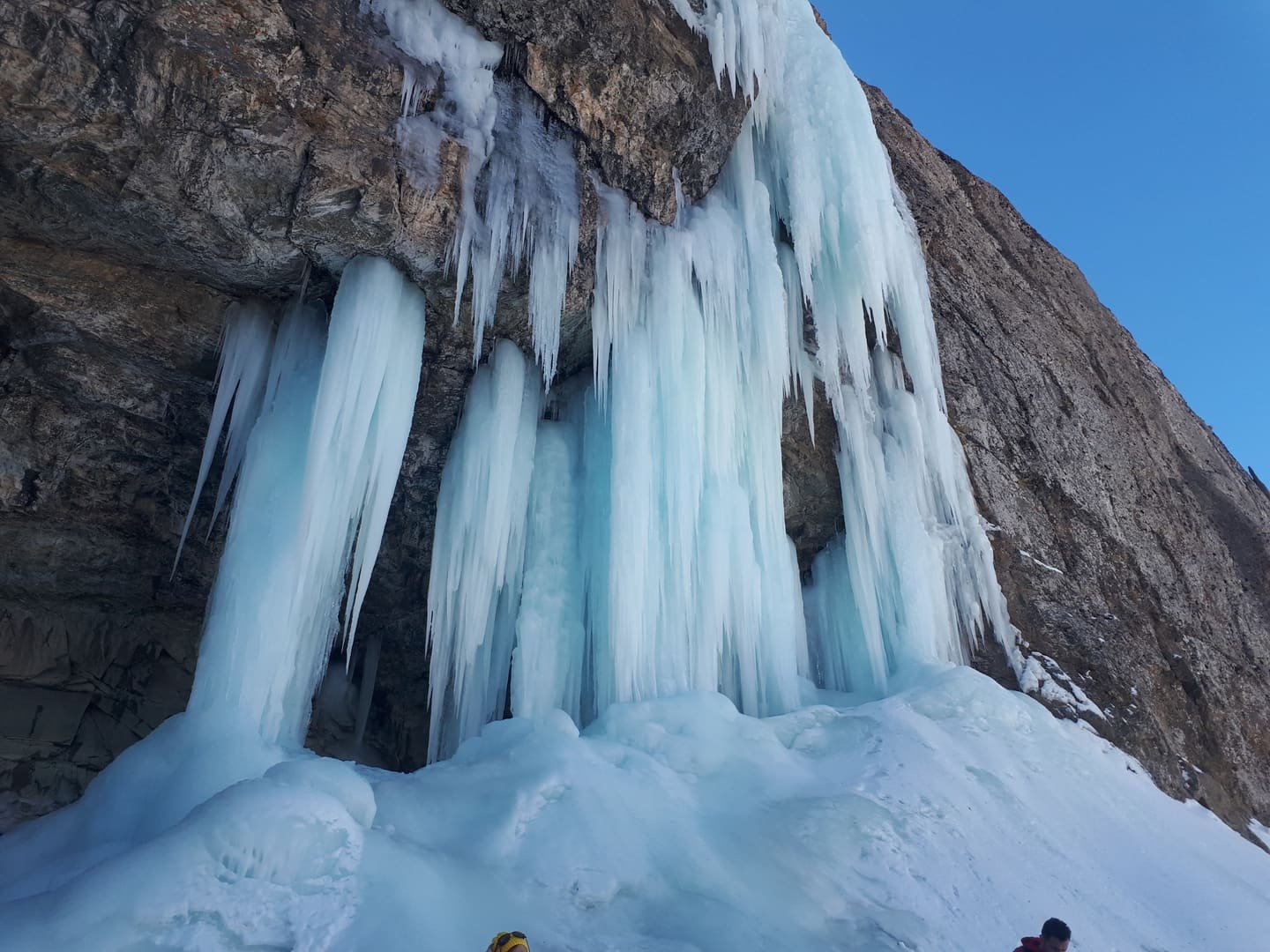 A vast blue frozen waterfall hanging down a rock face