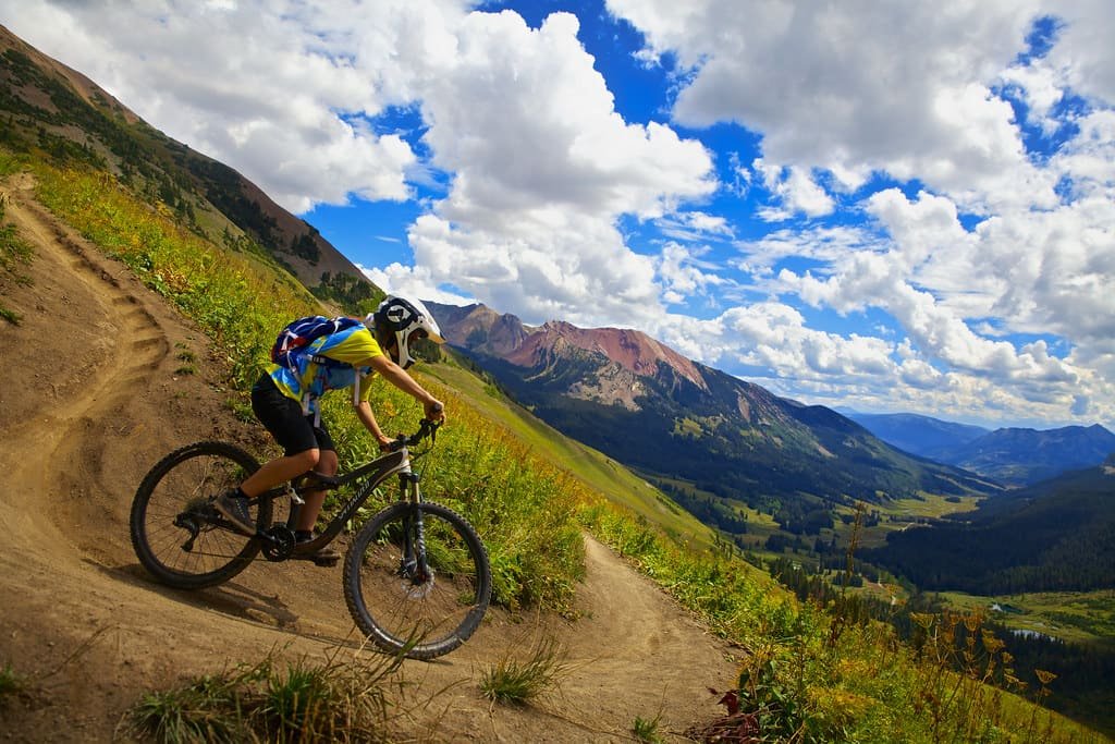 A mountain biker riding a singletrack trail high above a valley