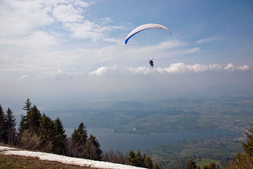 A paraglider flying high above a layer of cloud