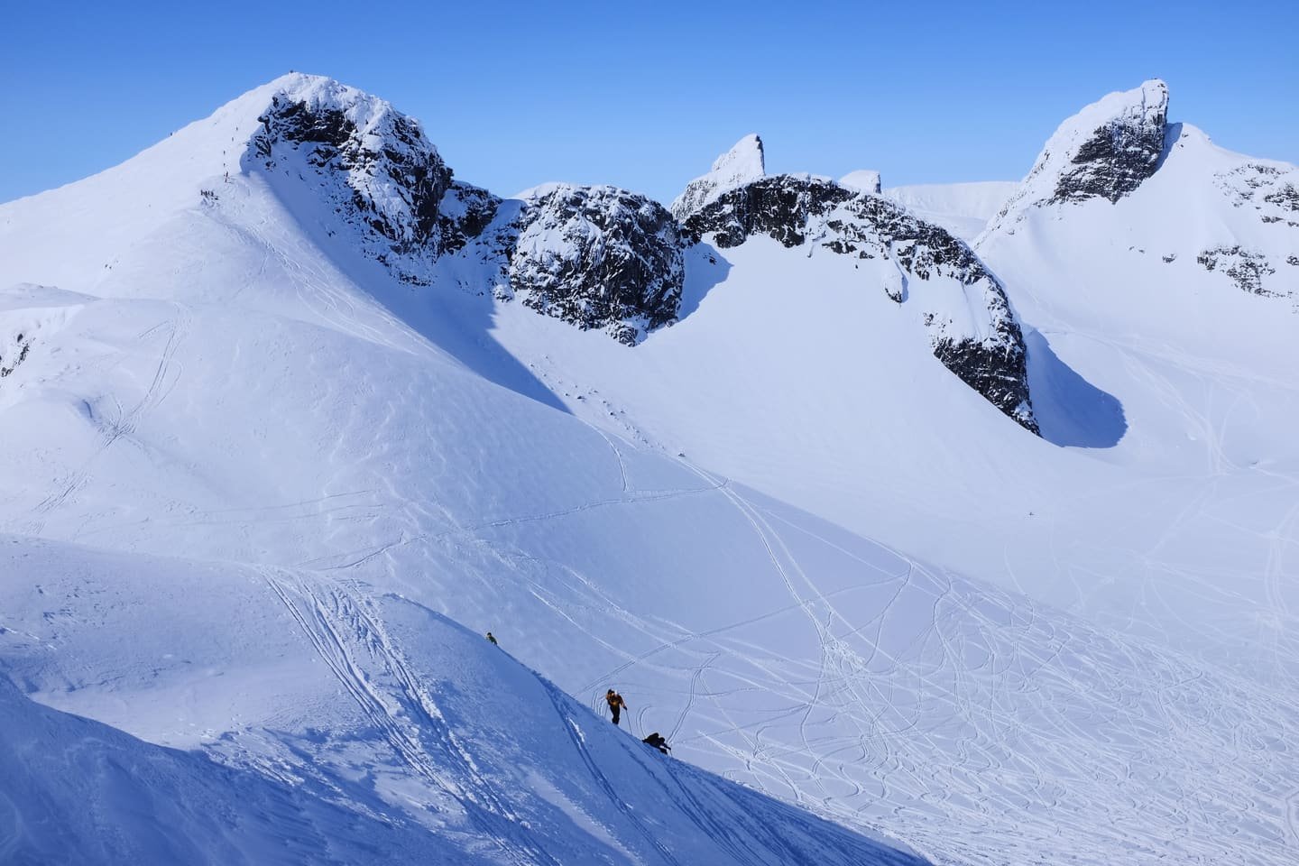 A ski tourer crossing a wide snowfield beneath rock summits