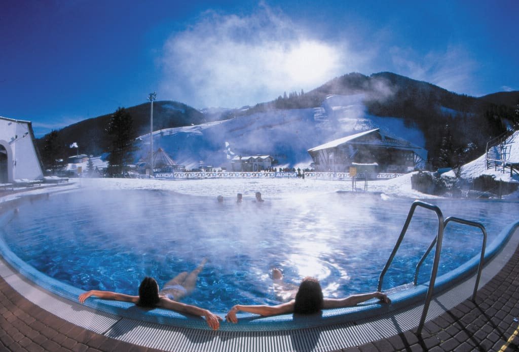 Steam rising from an outdoor thermal pool surrounded by snow