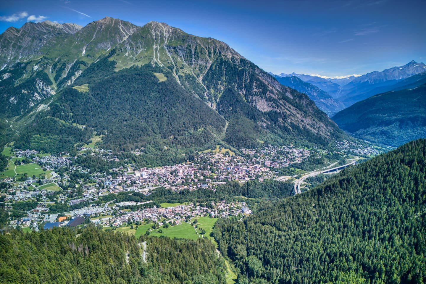 A town spread along the floor of a deep alpine valley seen from above