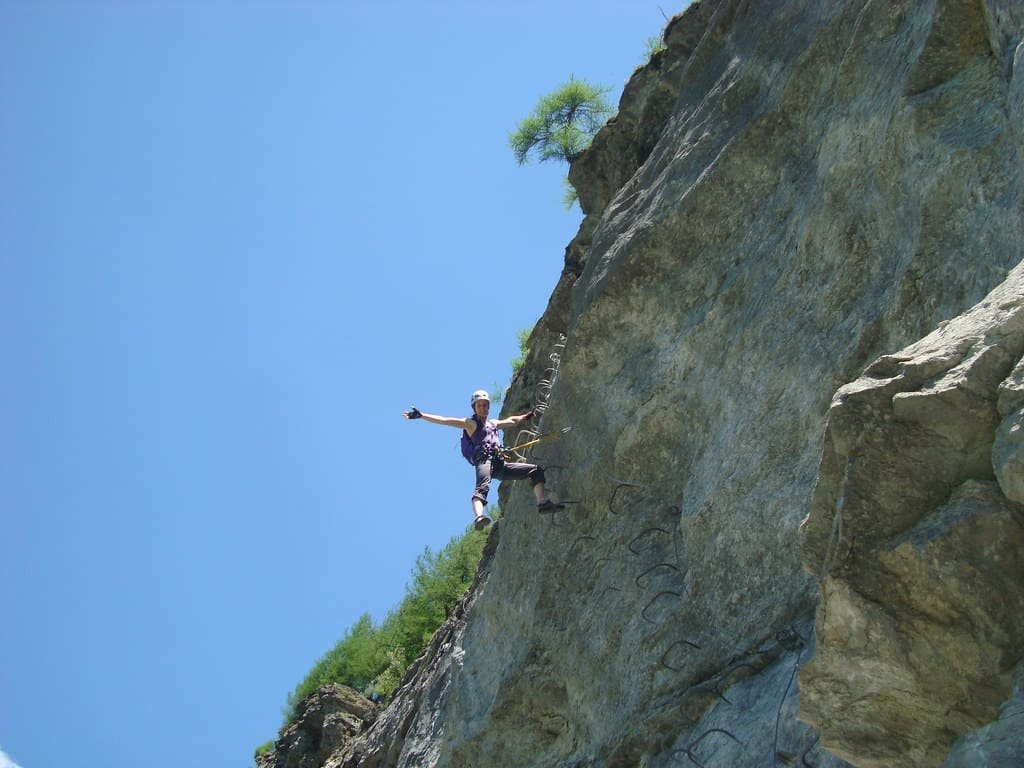 A climber clipped to the cable of a via ferrata on a vertical wall